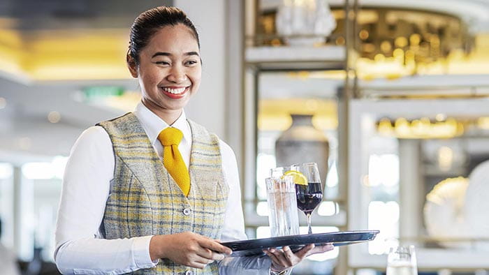 A passenger being served drinks in the Britannia Lounge by a member of staff on Spirit of Adventure